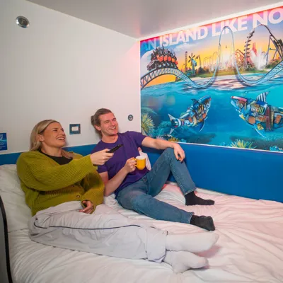 Guests sat on top of the bed watching the Tv in a Thorpe Shark Cabin